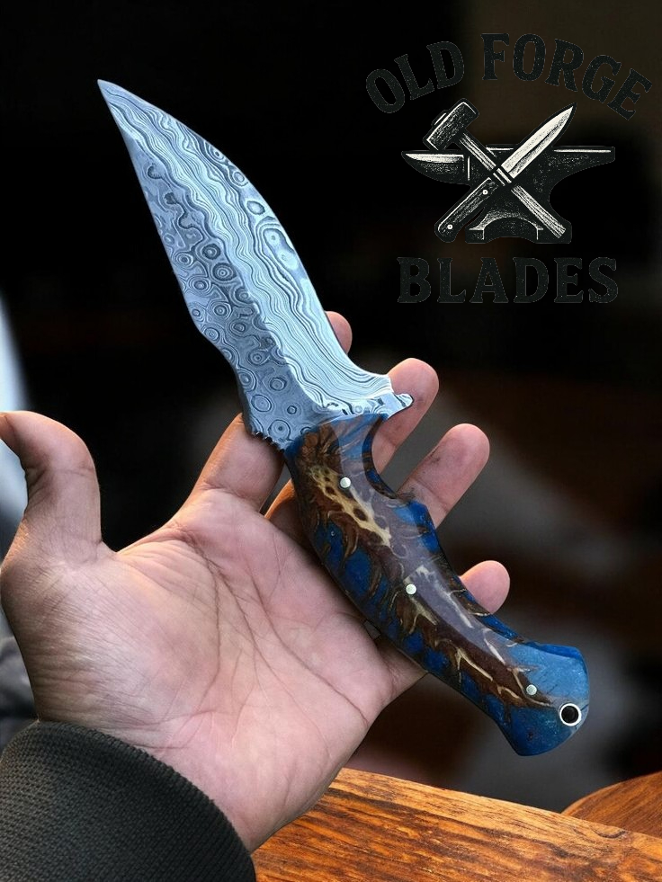 Hand holding a Damascus knife with a detailed handle, branded 'Old Forge Blades' in the background.