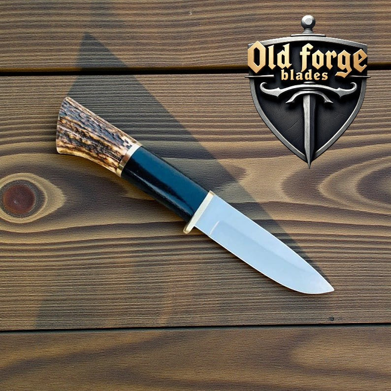 Close-up of deer hunting knife showing antler handle and patterned blade